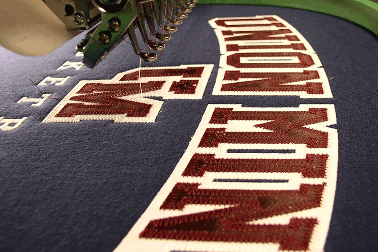 An embroidered team initial on the sewn tip of a custom softball belt